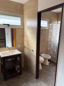 a bathroom with a sink and a toilet and a mirror at Duplex confortable en Caleta Olivia in Caleta Olivia