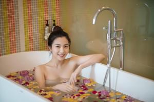 a woman laying in a bath tub filled with flowers at Jaya Suites Hotel in Phnom Penh