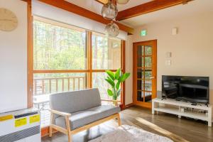 a living room with a chair and a television at Origami Chalet - Riverside in Hakuba