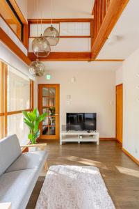 a living room with a couch and a tv at Origami Chalet - Riverside in Hakuba