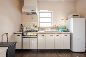 a kitchen with white cabinets and a white refrigerator at Origami Chalet - Riverside in Hakuba +14 photos
