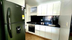 Una cocina con un refrigerador verde y gabinetes blancos. en Apartaestudio cerca centros comerciales -Refugio romantico, en Ibagué