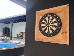 a dart board on a wall next to a pool at Trébol House Hostel in La Ceiba