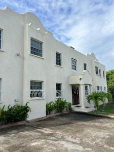 a white building with a driveway in front of it at Oistins Gem 2BR, 2BA Condo, Pool & Rooftop Patio, Walk to Miami Beach in Christ Church