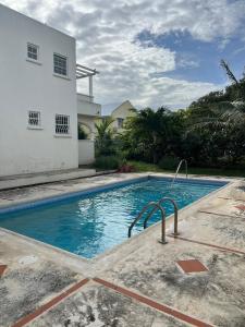 a swimming pool in front of a house at Oistins Gem 2BR, 2BA Condo, Pool & Rooftop Patio, Walk to Miami Beach in Christ Church