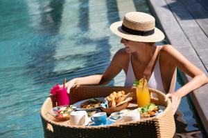 a woman sitting next to a pool with a tray of food at Emana Abiantaksu in Mantaak