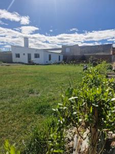 Un campo con un edificio blanco al fondo en Hospedaje El Quincho, en Gobernador Gregores