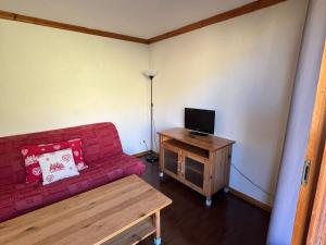 a living room with a red couch and a wooden table at Appartement Montagne 4 Pers, Balcon et Piscine - FR-1-814-162 in Super Besse