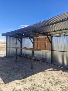 Un pabellón de metal con una mesa de picnic y bancos. en Hospedaje El Quincho2, en Gobernador Gregores 2 fotos más