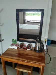 a mirror on top of a wooden table with a tea kettle at DODAND Studio & Sunset Riverside Guesthouse in Don Det