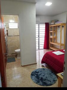 a bedroom with a red bed and a bathroom at La fortaleza A una cuadra de la terminal in Concordia
