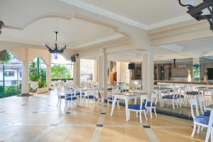 una sala da pranzo con tavoli e sedie bianchi di Horison Resort Tulip Puncak a Cipanas