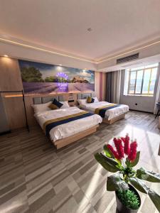 a bedroom with two beds and a painting on the wall at Wang Tian Shu Value Resort Hotel in Mengla