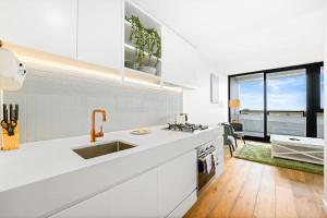 a white kitchen with a sink and a counter at Galleria - Sleek & Sunlit Living in Glen Waverley in Glen Waverley