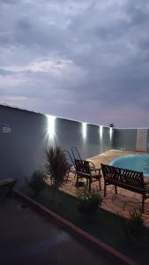 a patio with two benches and a swimming pool at Canto dos Pássaros in Igarassú +2 photos