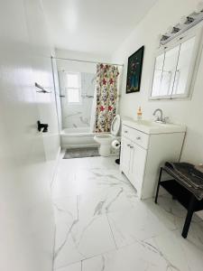 a white bathroom with a toilet and a sink at Spacious 4Bdrs house with parking in Hempstead