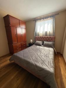 a bedroom with a large bed and a dresser at Encanto Colonial Apartamento Centro Histórico in Cuenca