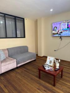 a living room with a couch and a tv at Encanto Colonial Apartamento Centro Histórico in Cuenca