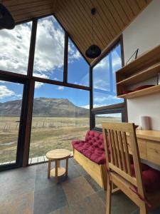 Habitación con banco, mesa y ventanas en Cabañas Montañas Patagónicas, en Puerto Natales