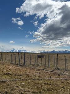 una valla en un campo con montañas en el fondo en Cabañas Montañas Patagónicas, en Puerto Natales 2 fotos más