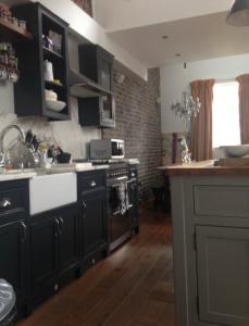 una cocina con armarios negros y un horno de fogón blanco en The Snug in a Quaint English Mews House, en Londres