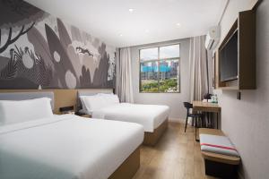 a hotel room with two beds and a tv at Thank You Hotel Sanya Bay Coconut Dream Corridor Branch in Sanya