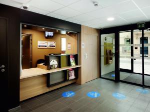 a lobby with a waiting room with a tv on the wall at B&B HOTEL Castres Centre Gambetta in Castres