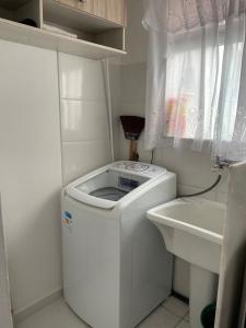 a white washing machine in a bathroom with a sink at Comfort and good memories, right by the lagoon! in São Pedro da Aldeia