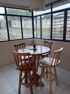 Una mesa y sillas en una habitación con ventanas. en The Deyzel House, en Durban 13 fotos más