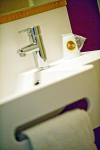 B&B HOTEL Marne-La-Vallée Torcy في تورسي: بالوعة الحمام بها صنبور ومنشفة