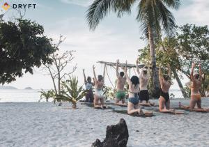 a group of people doing yoga on the beach at Dryft Darocotan Island in El Nido