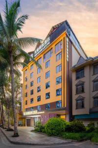 een hotel met een palmboom ervoor bij Mehood Lestie in Jinghong