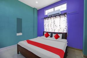 1 dormitorio con paredes azules y 1 cama con almohadas rojas en Hotel O Brahmaputra Stay, en Dibrugarh