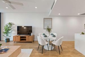 a dining room with a table and chairs and a tv at Brisbane City 2BR Apartment River and Fireworks View in Brisbane
