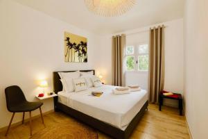 ein Schlafzimmer mit einem großen Bett und einem Stuhl in der Unterkunft Appartement La Perle - Village Creole in Lazaret