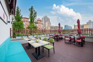 un patio avec tables et chaises sur un balcon dans l'établissement 上海艾菲花园酒店The Garden F, à Shanghai