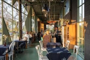 a restaurant with blue tables and white chairs and people at STAY PILAFarm in Ban Nam Chun Yai