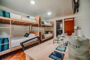 a room with two bunk beds and a table with glasses at Casa Andora in Machu Picchu