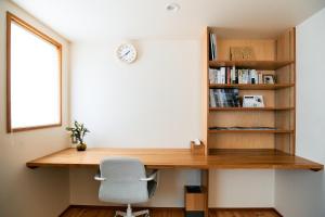 a desk with a chair and a clock on a wall at Kiyose Garden Stay - 最大10名でゆったり過ごせる宿 in Matsuyama