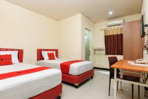 a hotel room with two beds and a desk at RedDoorz Plus @ Jalan Pemuda Jakarta in Jakarta +36 photos