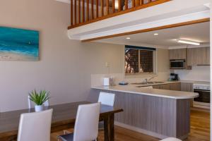 een keuken met een houten tafel en witte stoelen bij Angourie BAY Villa - Unit 1 in Yamba +8 foto's