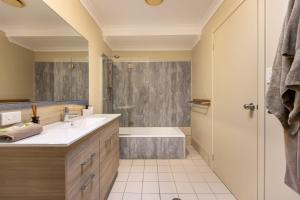 een badkamer met een wastafel, een bad en een douche bij Angourie BAY Villa - Unit 1 in Yamba