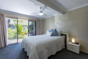een slaapkamer met een bed en een groot raam bij Angourie BAY Villa - Unit 1 in Yamba