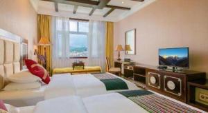 Una habitación grande con una cama grande y un televisor. en Shangri-la Zhaxidele Hotel, en Shangri-La