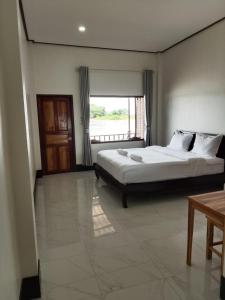 a bedroom with a large bed and a window at DODAND Studio & Sunset Riverside Guesthouse in Don Det