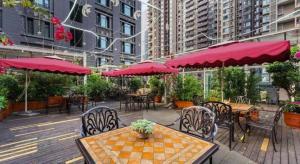 a patio with tables and chairs and red umbrellas at James Joyce Coffetel Chengdu Jianshe Road Dongjiao Jiyi Square in Chengdu