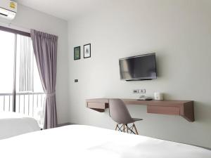 a hotel room with a desk and a tv at @Sleep in Nakhon Pathom