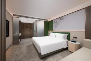 a bedroom with a white bed and a green wall at Mehood Lestie Hotel, Nanjing Xinjiekou Subway Station in Nanjing