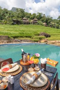 a table with plates of food and drinks and a pool at Pu Luong EcoLuxe Resort & Spa in Lũng Tiềm