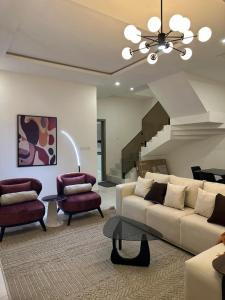 a living room with a couch and chairs and a staircase at CrystalsLodge in Ibeju